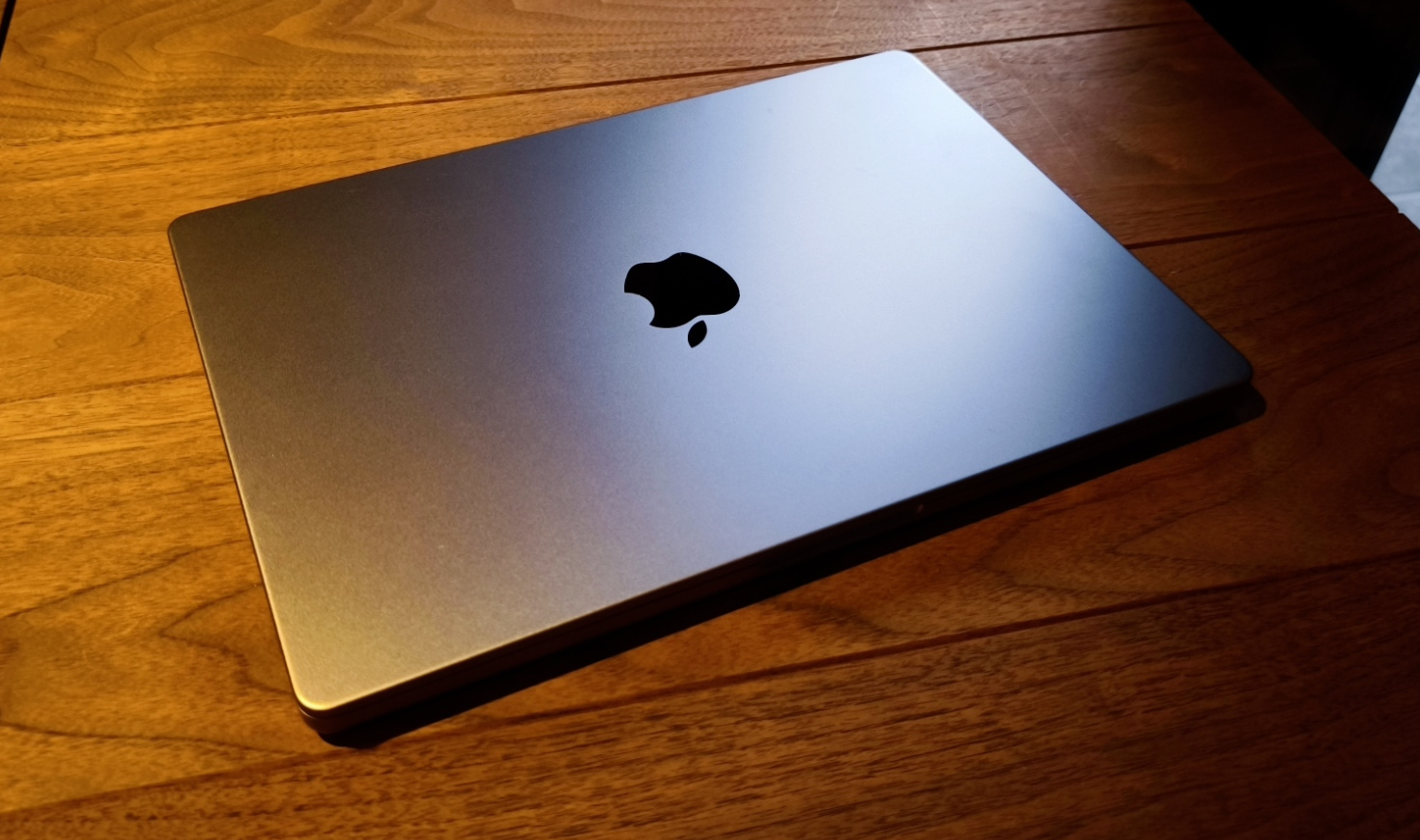 木のテーブルの上に閉じて置かれたMacBook